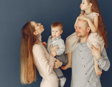 Portrait of a joyful family with parents and kids showing love and affection against a blue background.